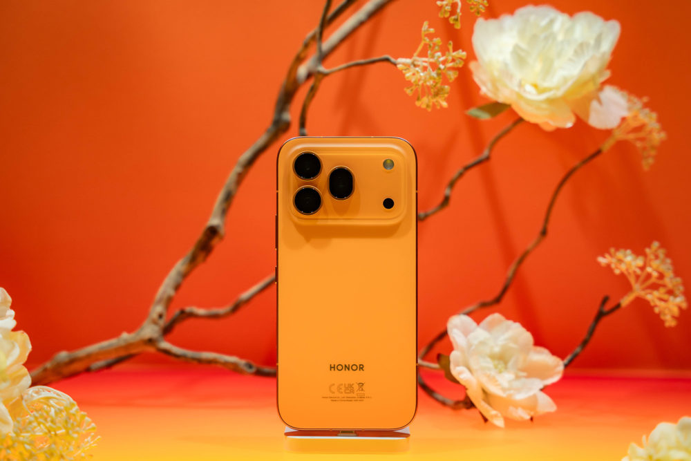 Teléfono inteligente Honor color naranja sobre fondo floral anaranjado, destacado por su elegante diseño y cámaras.