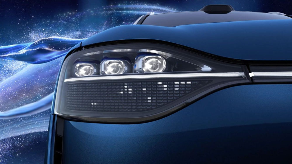 Primer plano de faro delantero de auto eléctrico azul, diseño futurista con fondo de galaxia estrellada.