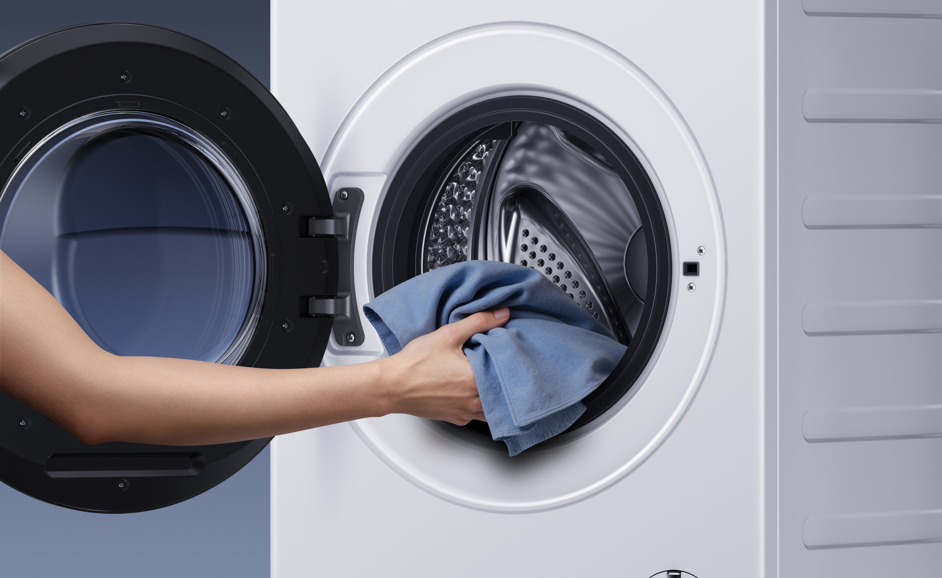 Persona colocando ropa en lavadora moderna de carga frontal.