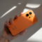 Teléfono Honor naranja sostenido por una mano, iluminado por la luz solar directa.