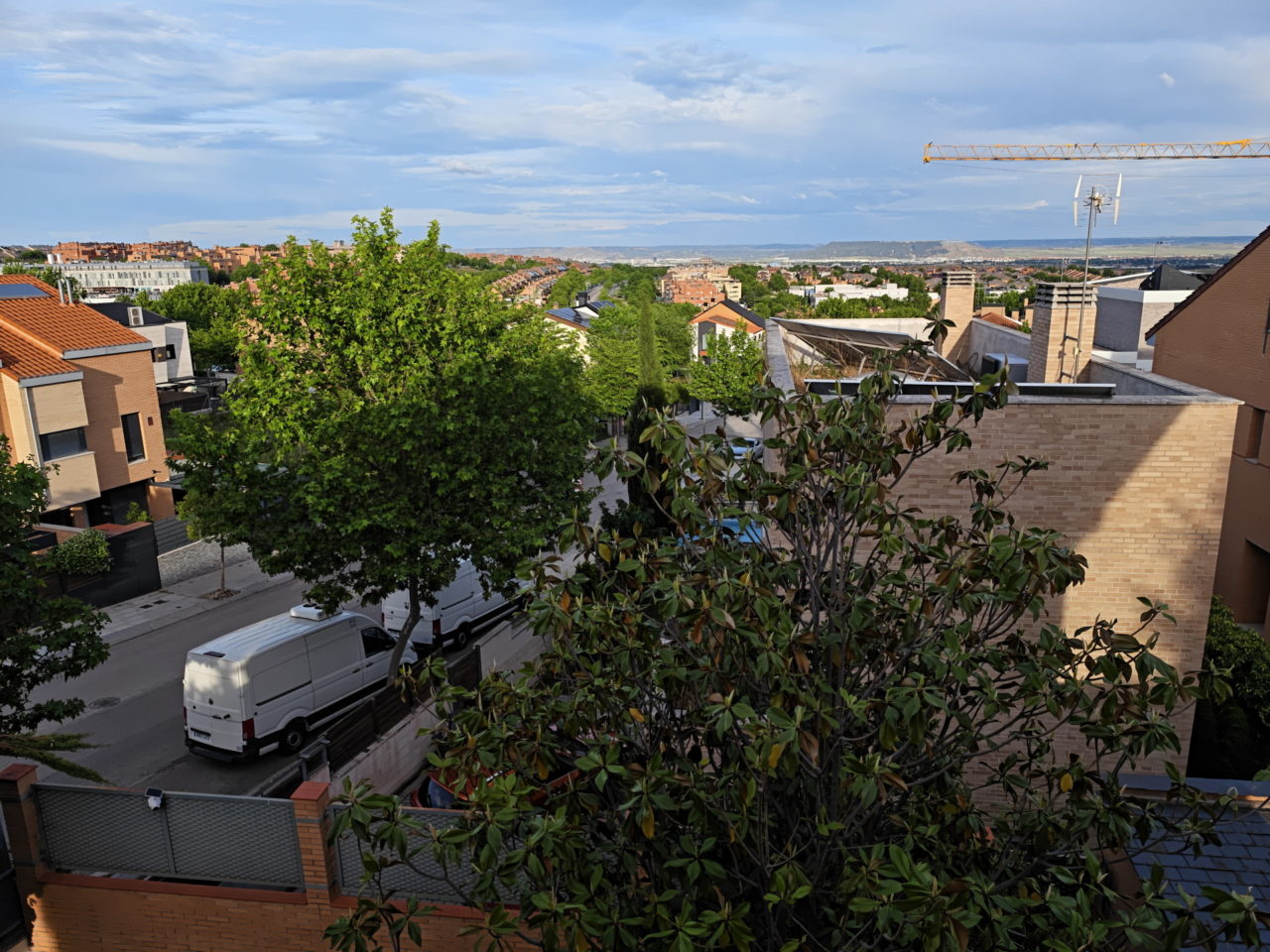 Vista aérea de un barrio residencial con casas modernas, árboles verdes y cielo despejado en un día soleado.
