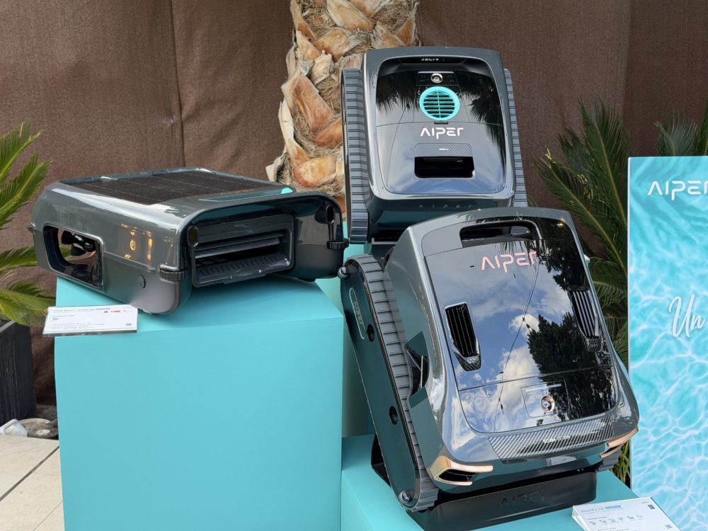 AIPER lleva la inteligencia artificial al jardín y la piscina con Scuba V3 e IrriSense 2 Robots limpia-piscinas Aiper expuestos sobre podio turquesa, innovadora tecnología para mantenimiento de piscinas.