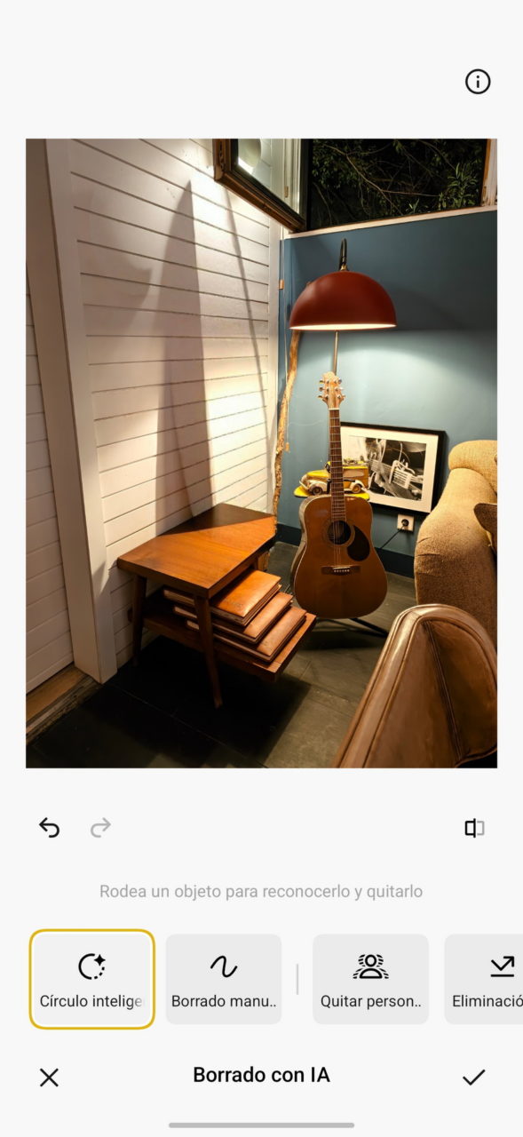 Guitarra acústica bajo lámpara de pie en esquina acogedora con mesa y sillón, ambiente cálido iluminado.