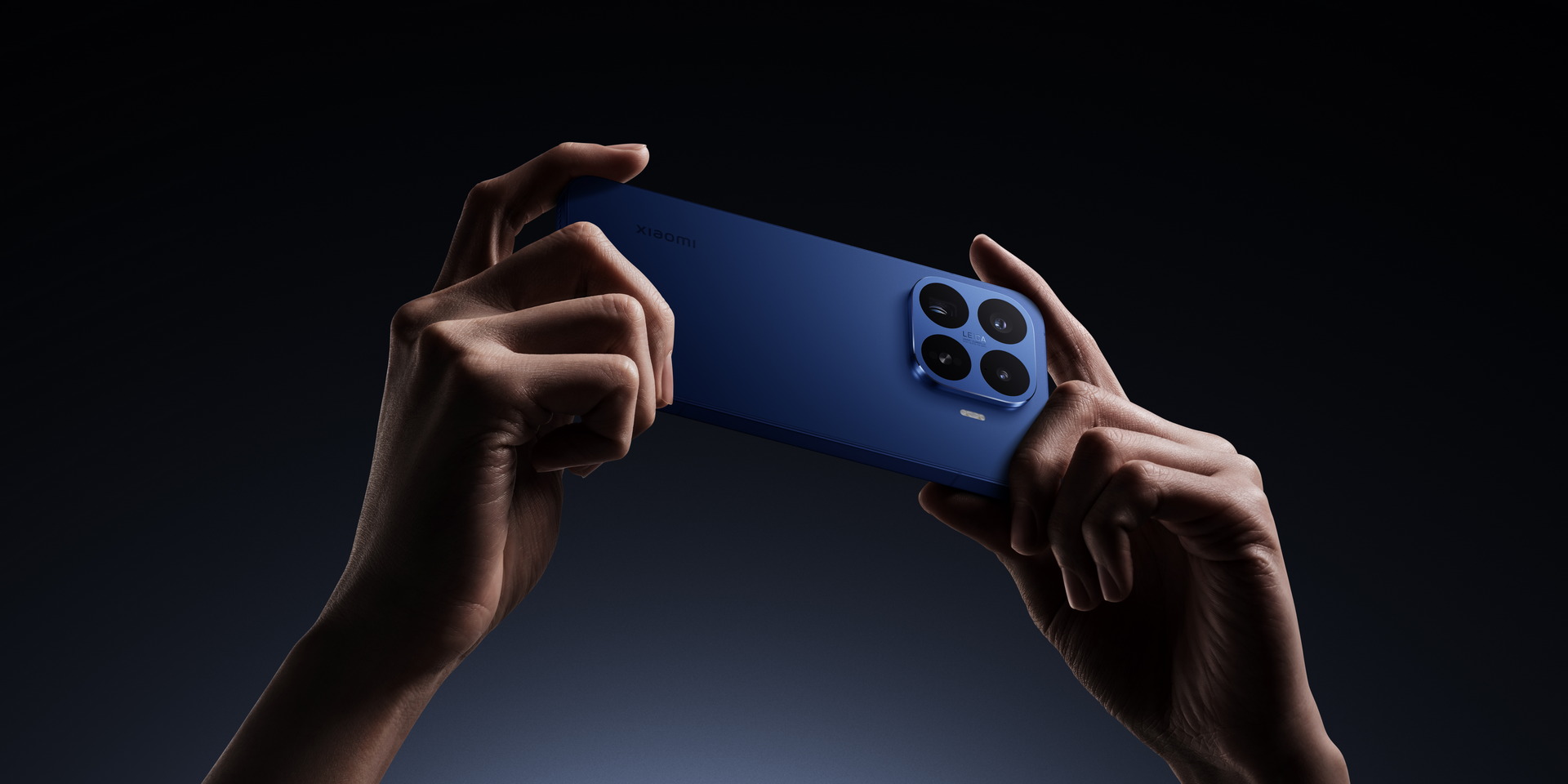 Manos sosteniendo un smartphone azul con triple cámara Leica en un fondo oscuro. Diseño elegante y moderno.