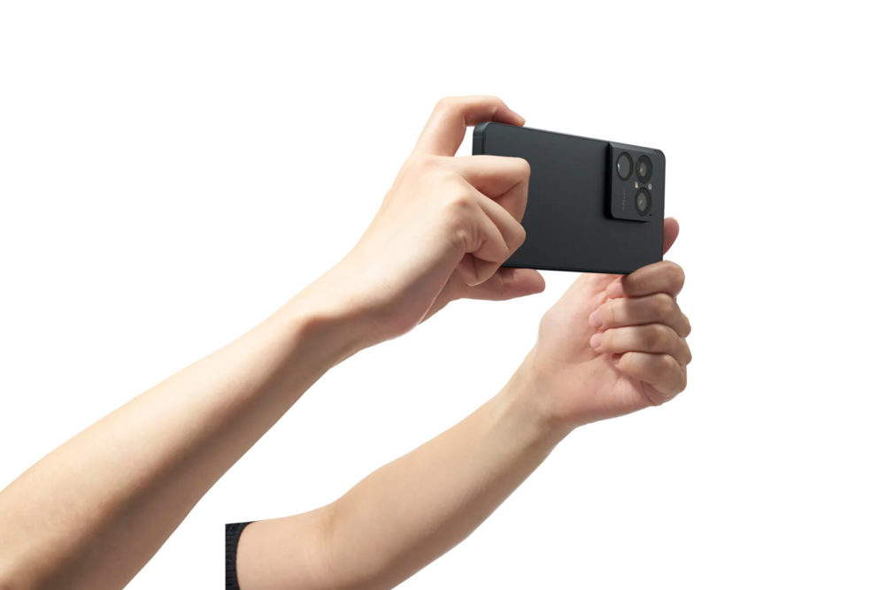 Sony Xperia 1 VIII: nuevo diseño, teleobjetivo gigante e IA para mejorar tus fotos Manos sosteniendo smartphone negro, con cámara de triple lente, para fotografía o video, fondo blanco.