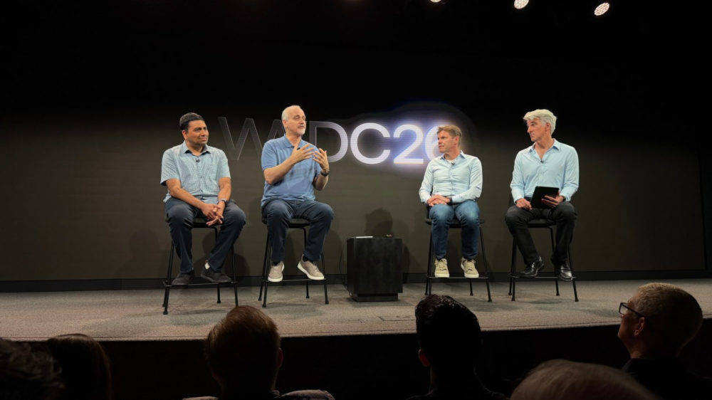 Personas en panel de discusión en conferencia tecnológica con fondo de logotipo WWDC, cuatro hombres sentados hablando.