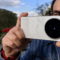 Persona usando un teléfono Vivo para fotografiar, destacando cámara Zeiss en un ambiente al aire libre.