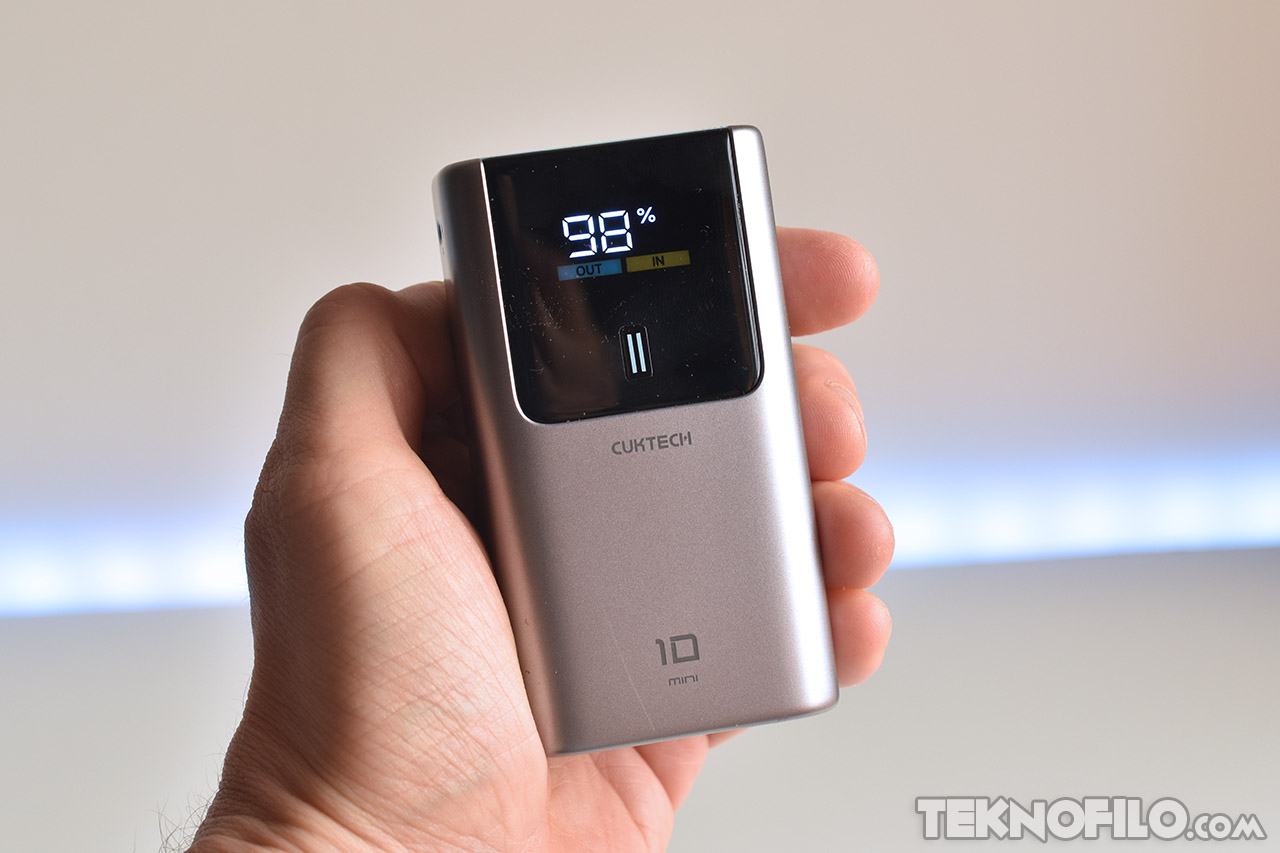 Power bank Cuktech 10 Mini en mano, mostrando carga al 98% en pantalla digital.