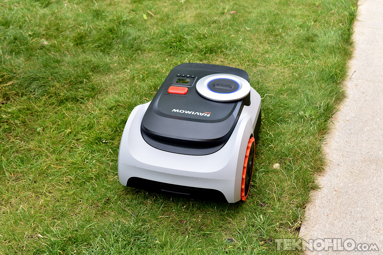 robot cortacésped automático en el césped verde junto a una acera