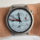 Reloj inteligente con esfera blanca y correa gris en la muñeca de un usuario.
