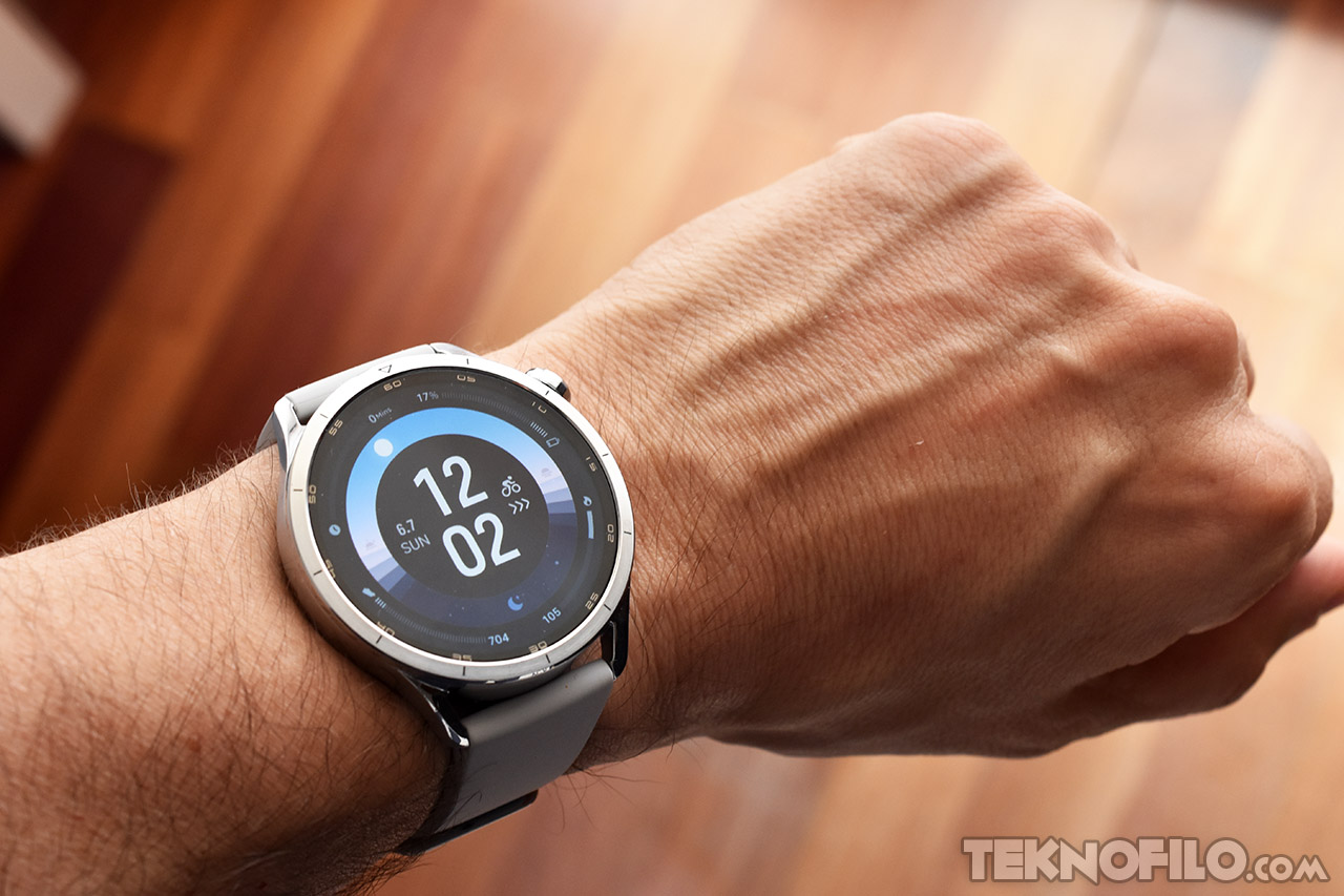 Reloj inteligente con esfera digital en la muñeca, mostrando la hora 12:02 y estadísticas de actividad física.