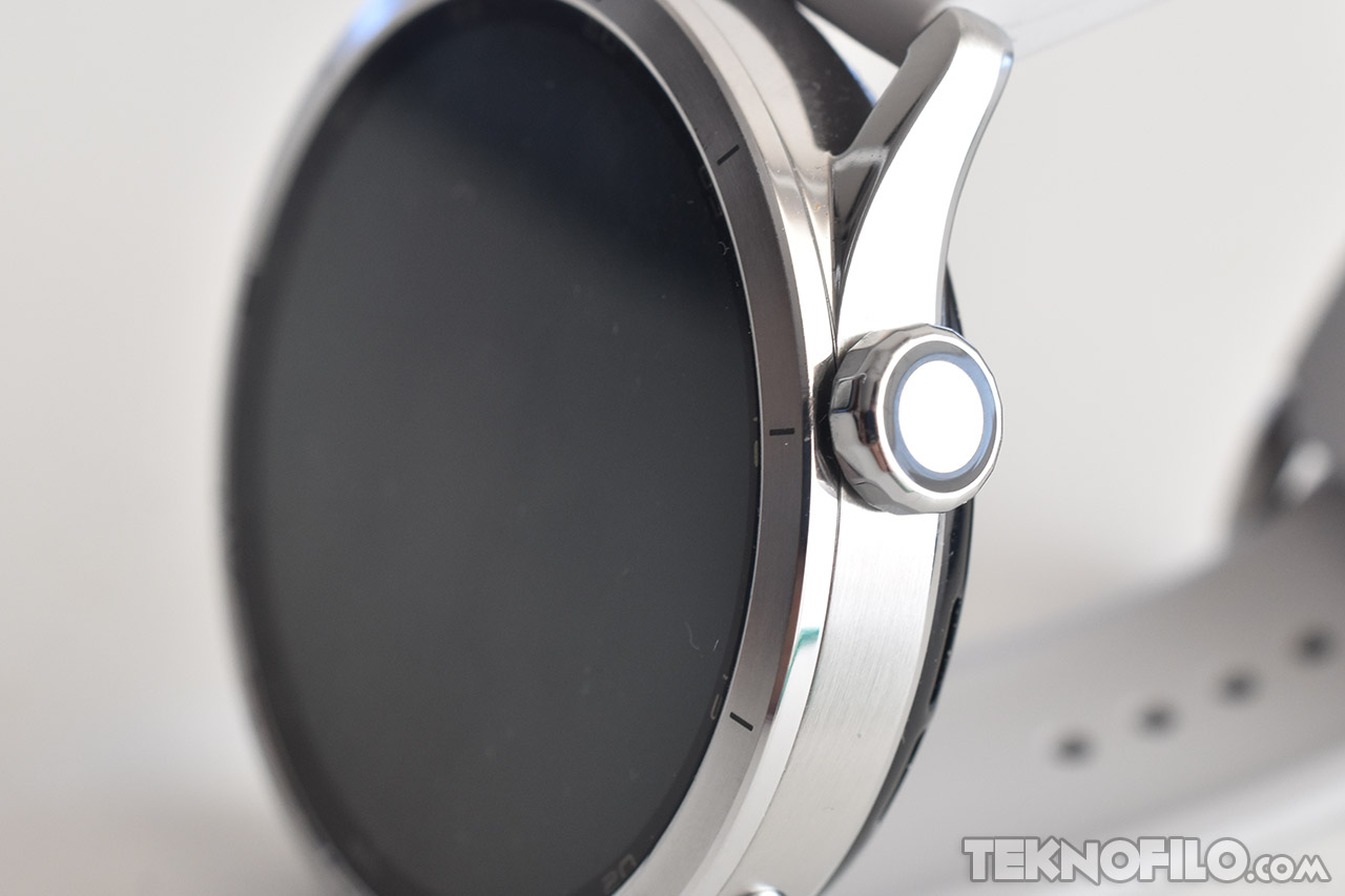 Reloj inteligente plateado con pantalla circular y corona lateral, diseño elegante y moderno.