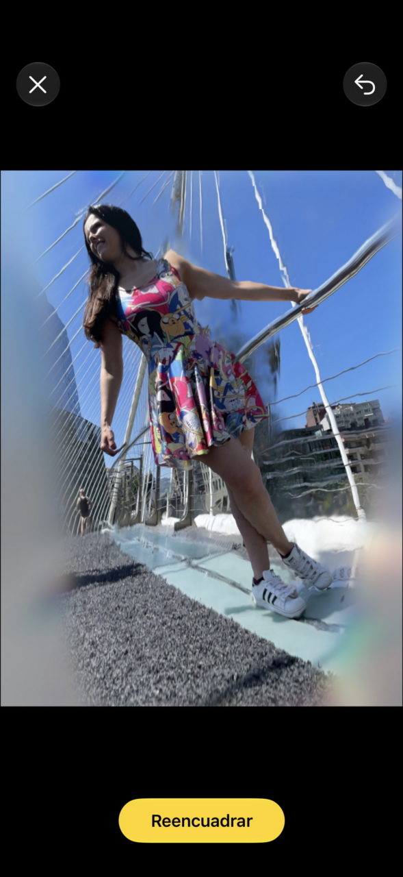 Mujer con vestido colorido posando en puente de vidrio bajo un cielo azul.
