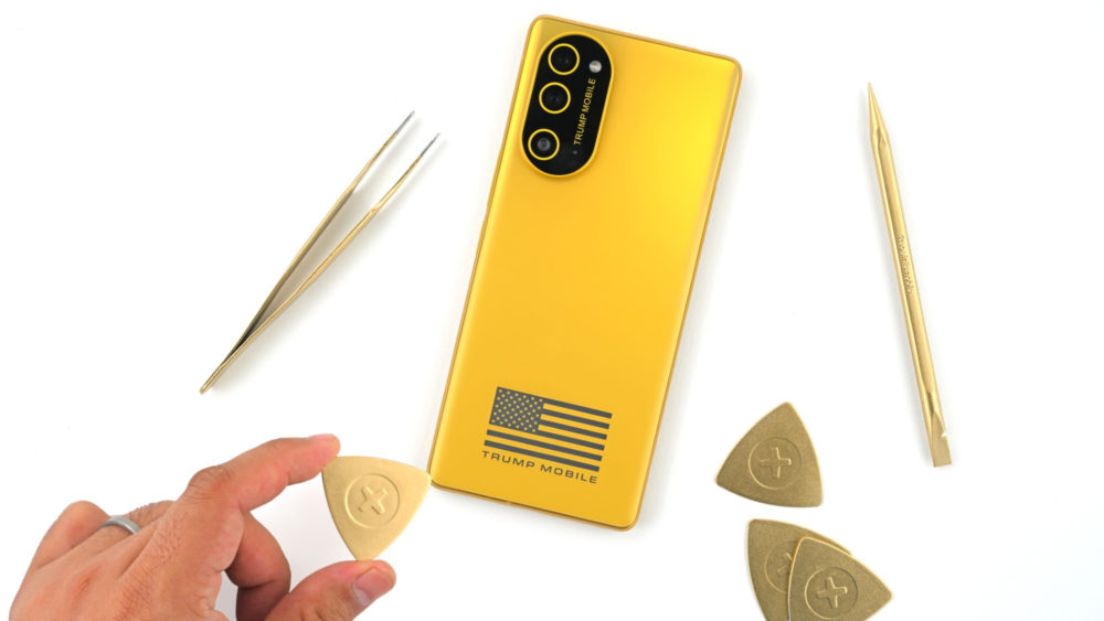 El Trump Mobile T1 es realmente un teléfono de HTC de 2024 con aspecto dorado Smartphone dorado con herramientas de reparación y logotipo en la parte trasera, visto desde arriba sobre fondo blanco.