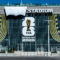 Fachada de estadio con anuncio de la Copa Mundial FIFA 2026, trofeo dorado y diseño moderno en la entrada.
