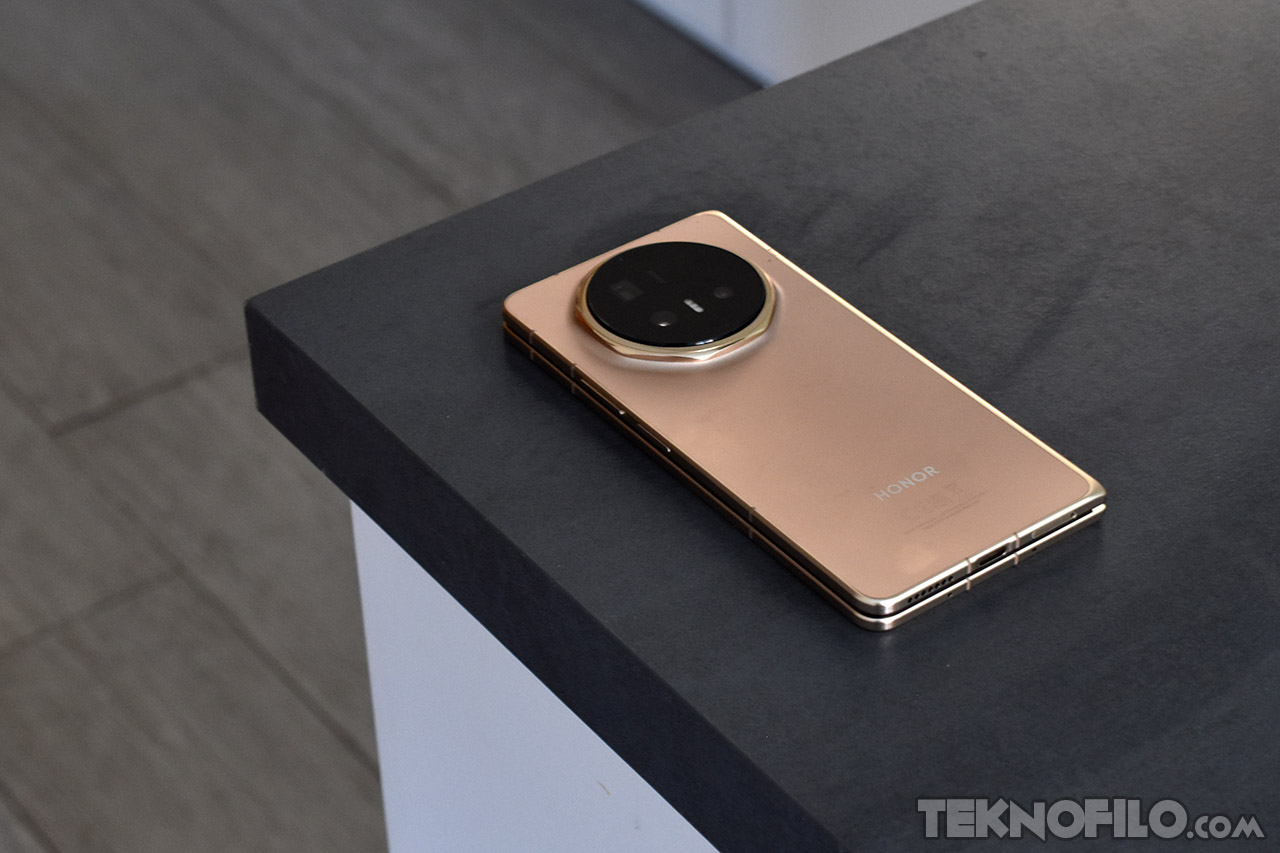 Smartphone Honor dorado en una mesa de madera oscura, mostrando su cámara circular trasera y diseño elegante.