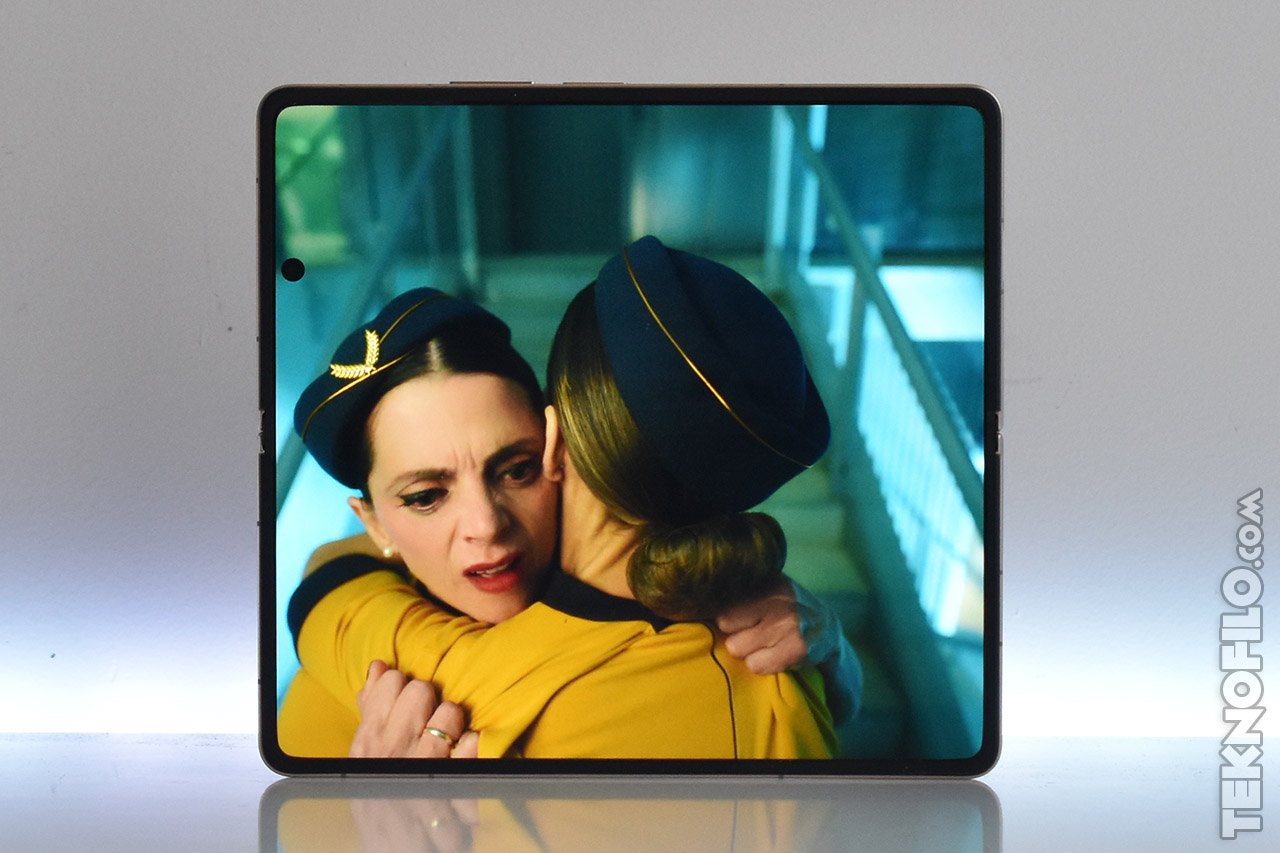Pantalla plegable mostrando escena emocional entre dos asistentes de vuelo.