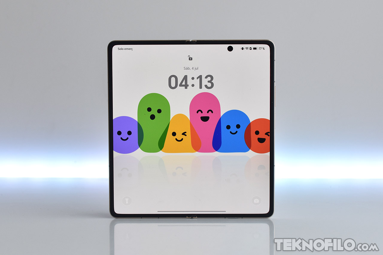 Pantalla plegable de smartphone con fondo de emojis coloridos y hora 04:13, sobre fondo claro.