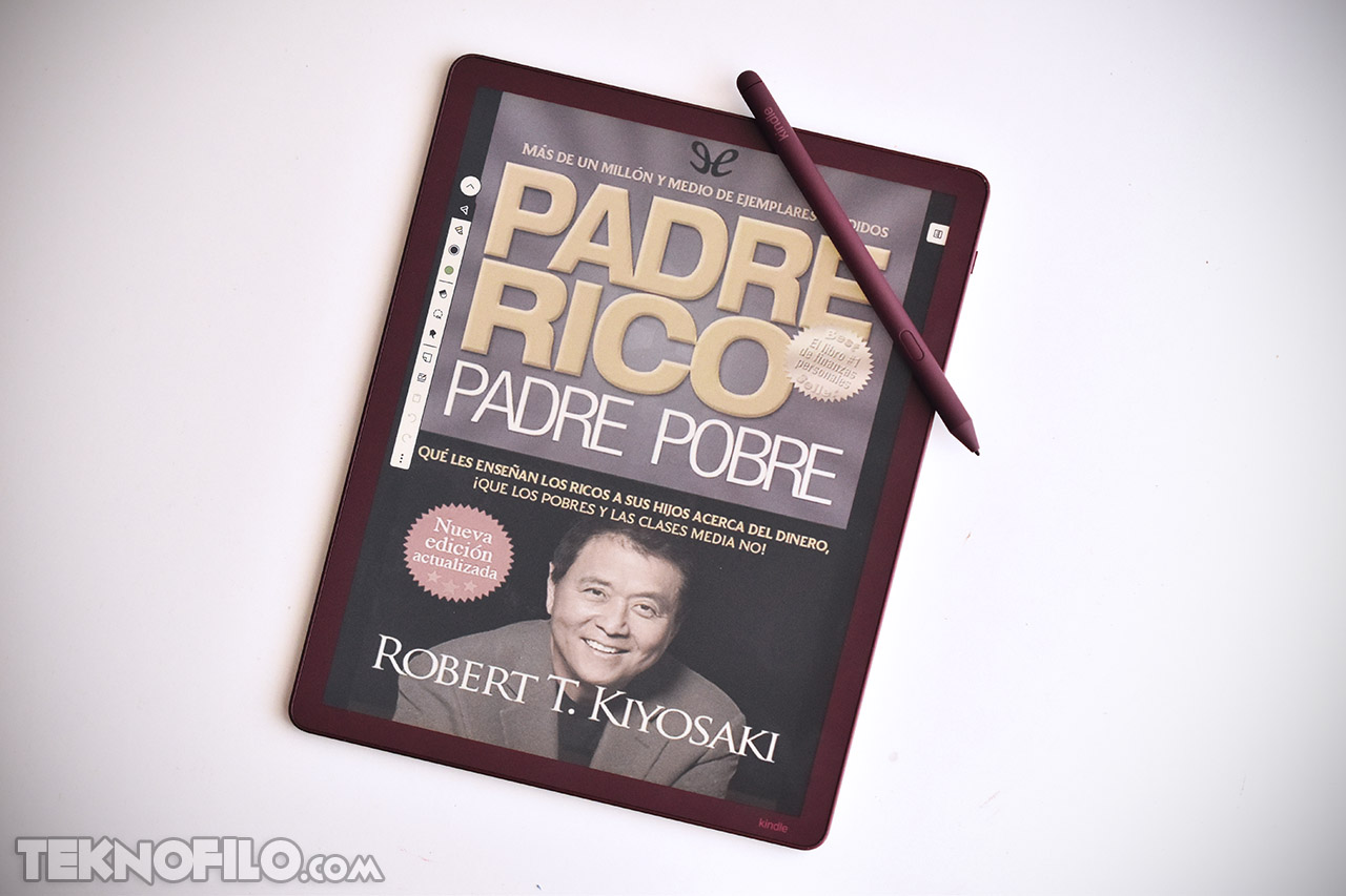 Ereader Kindle mostrando la portada de Padre Rico Padre Pobre de Robert T. Kiyosaki con un lápiz óptico al lado.