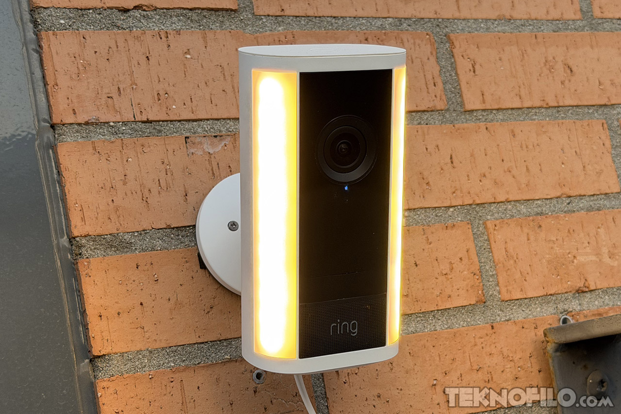 Cámara de seguridad Ring en pared de ladrillo, iluminada y lista para grabar en exteriores.