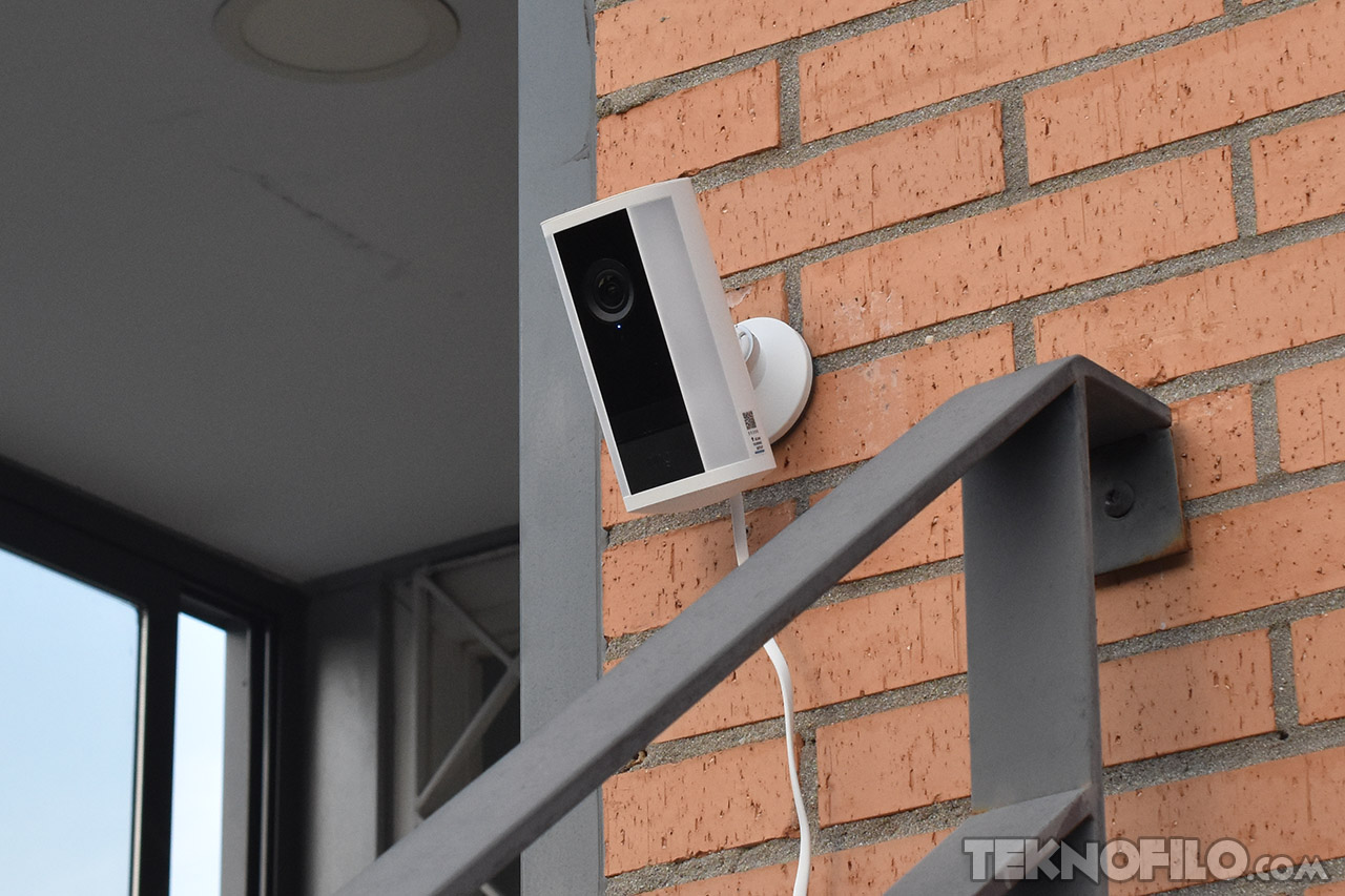 Cámara de seguridad montada en pared de ladrillo, capturando video exterior para vigilancia en hogar.