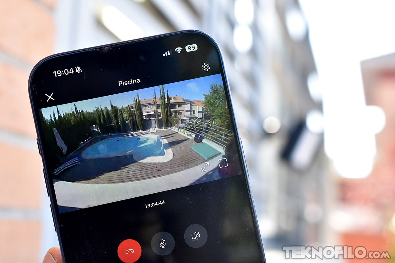 Móvil mostrando una transmisión en vivo de una piscina residencial a través de una app de cámaras de seguridad.