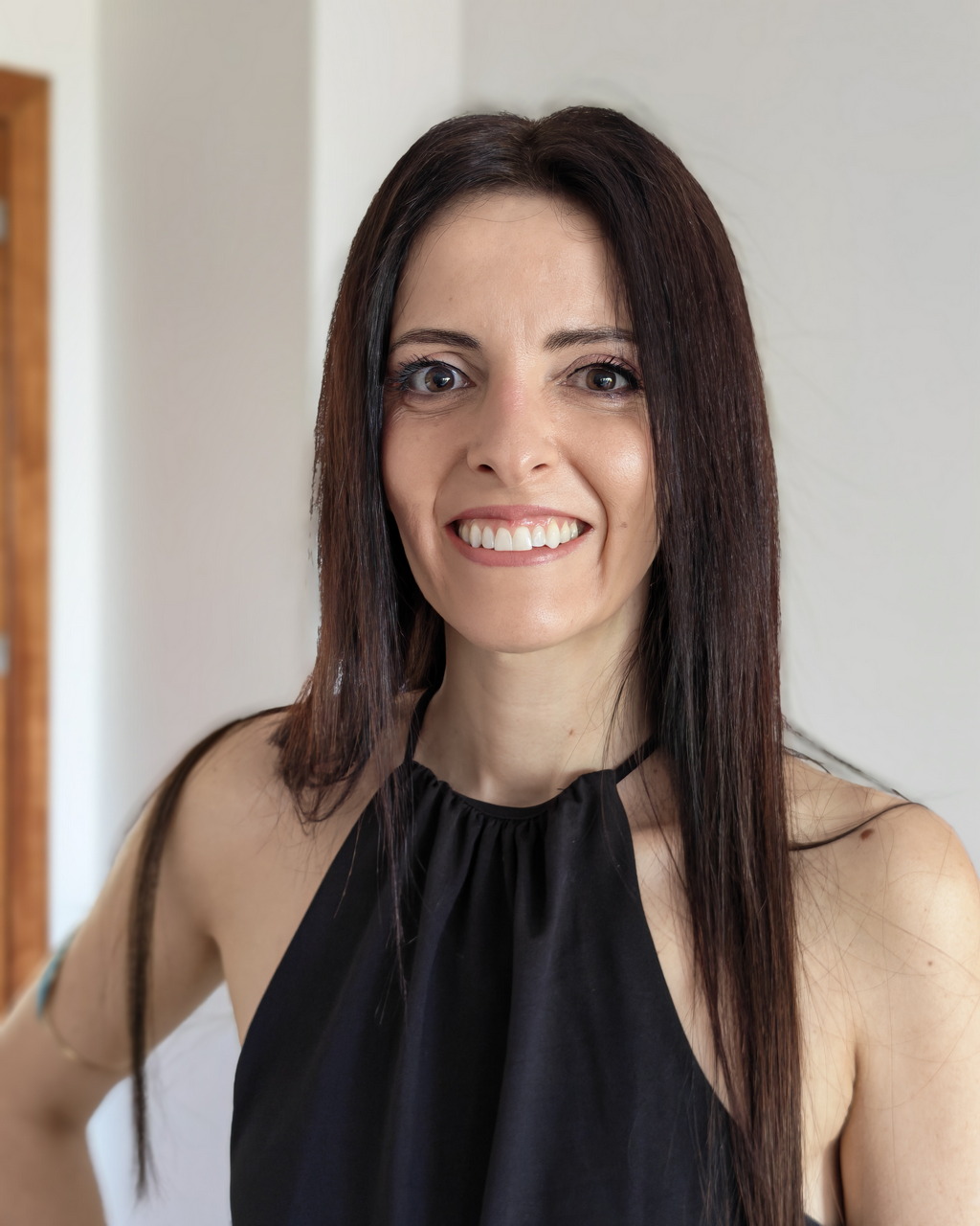Lo siento, no sé quién es en la foto.Sin embargo, aquí tienes el texto alternativo sugerido:Mujer sonriente con vestido negro y cabello largo, lacio, en interior iluminado.