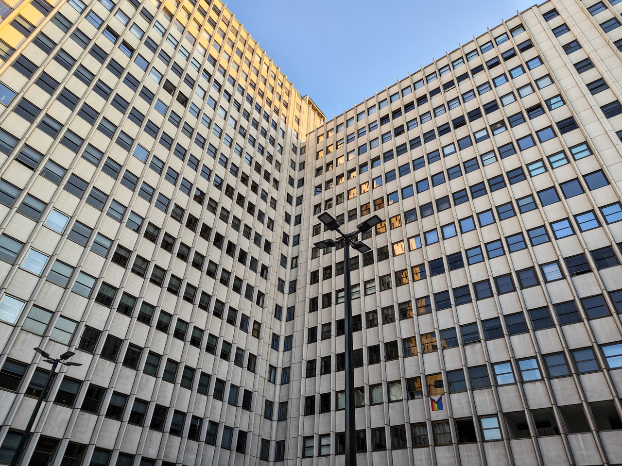 Edificio de oficinas alto con muchas ventanas en un día soleado, destacando un diseño moderno y simétrico.