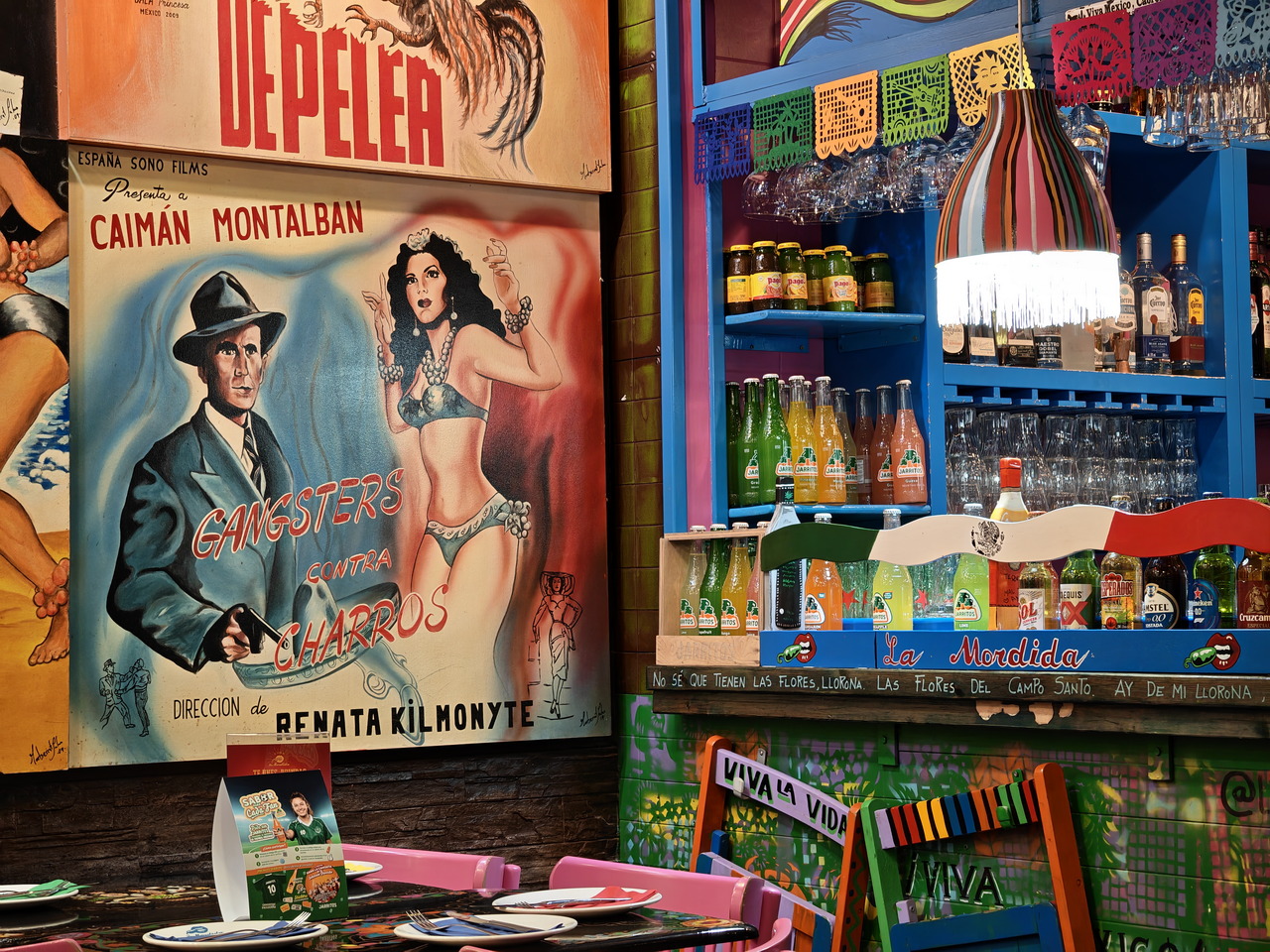 Cartel vintage de película Gangsters contra Charros en un colorido bar con botellas y sillas decorativas.