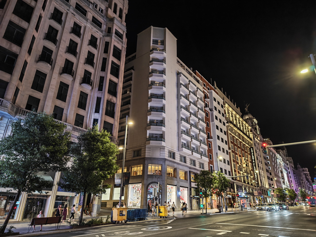 Calle Gran Vía de Madrid iluminada por la noche, destacando edificios y tráfico urbano.