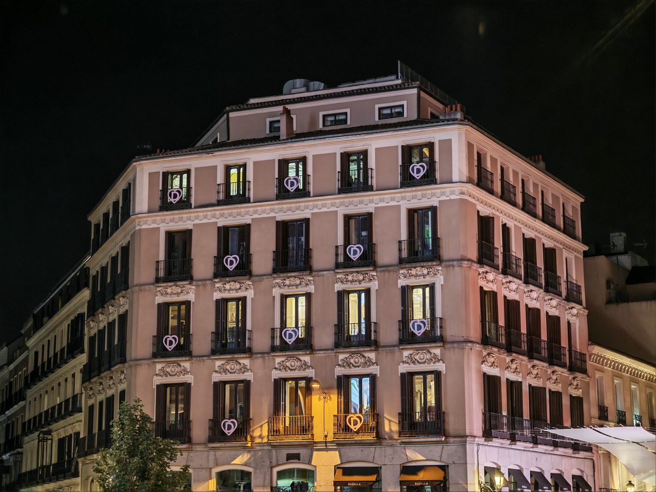 Edificio iluminado en el centro de la ciudad por la noche, con luces decorativas y balcones con corazones.