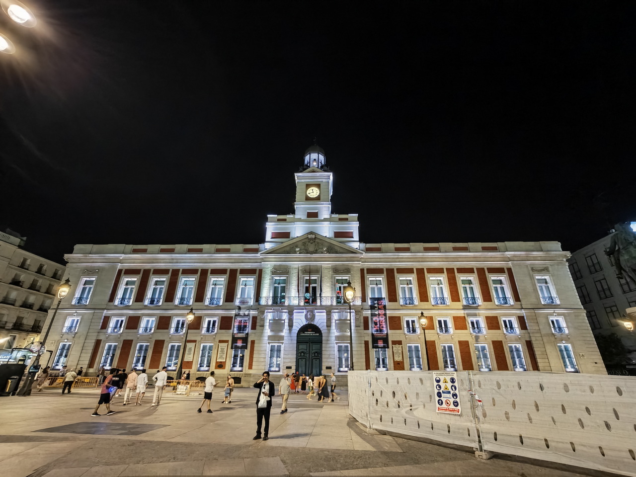 Fachada iluminada del edificio de la Real Casa de Correos en Puerta del Sol, Madrid, de noche.