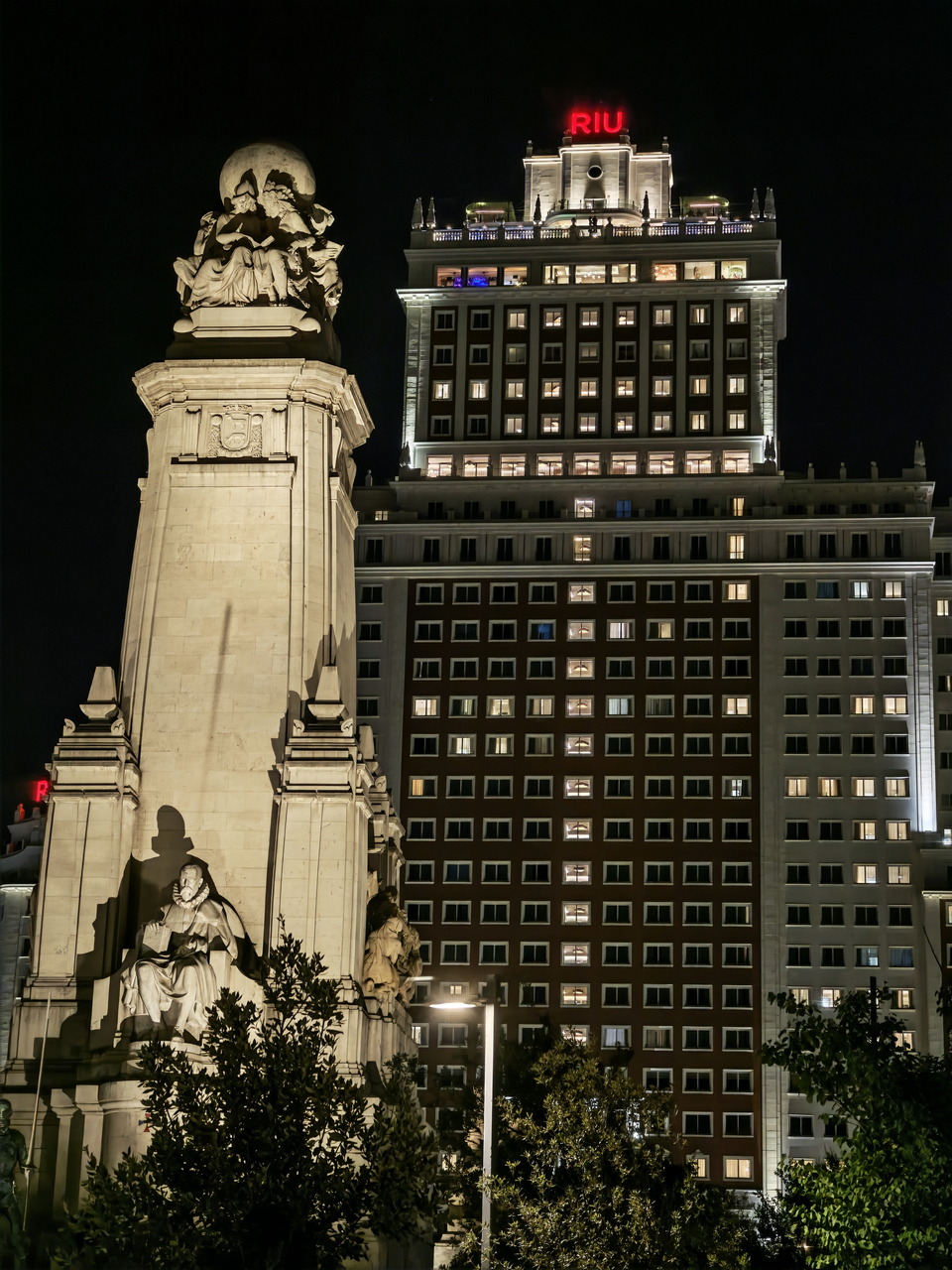 Monumento a Cervantes y edificio iluminado por la noche en Plaza de España, Madrid.