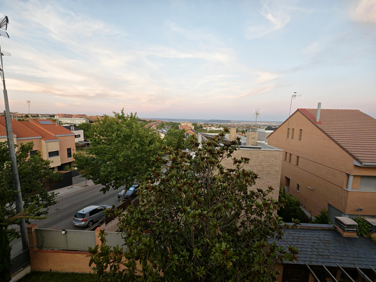 Vista de un barrio residencial con casas, árboles y cielo al atardecer.