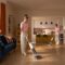 Roborock lanza las F25 Steam y F25 GT Gen 2: aspiración, fregado y vapor desde 299 euros Persona usando aspiradora en sala moderna con cocina al fondo, muebles coloridos y decoración acogedora.