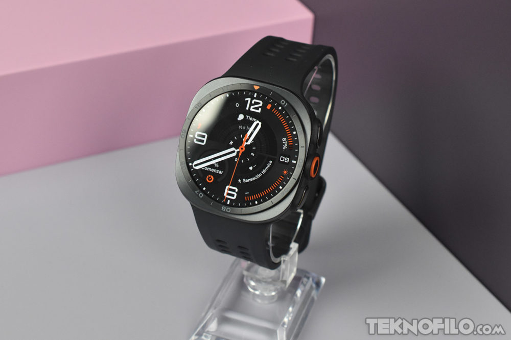 Samsung Galaxy Watch Ultra2 oficial: batería de 800 mAh y pantalla de 5.000 nits Reloj inteligente negro con pantalla analógica, sobre fondo rosa y gris. Ideal para fitness y estilo moderno.