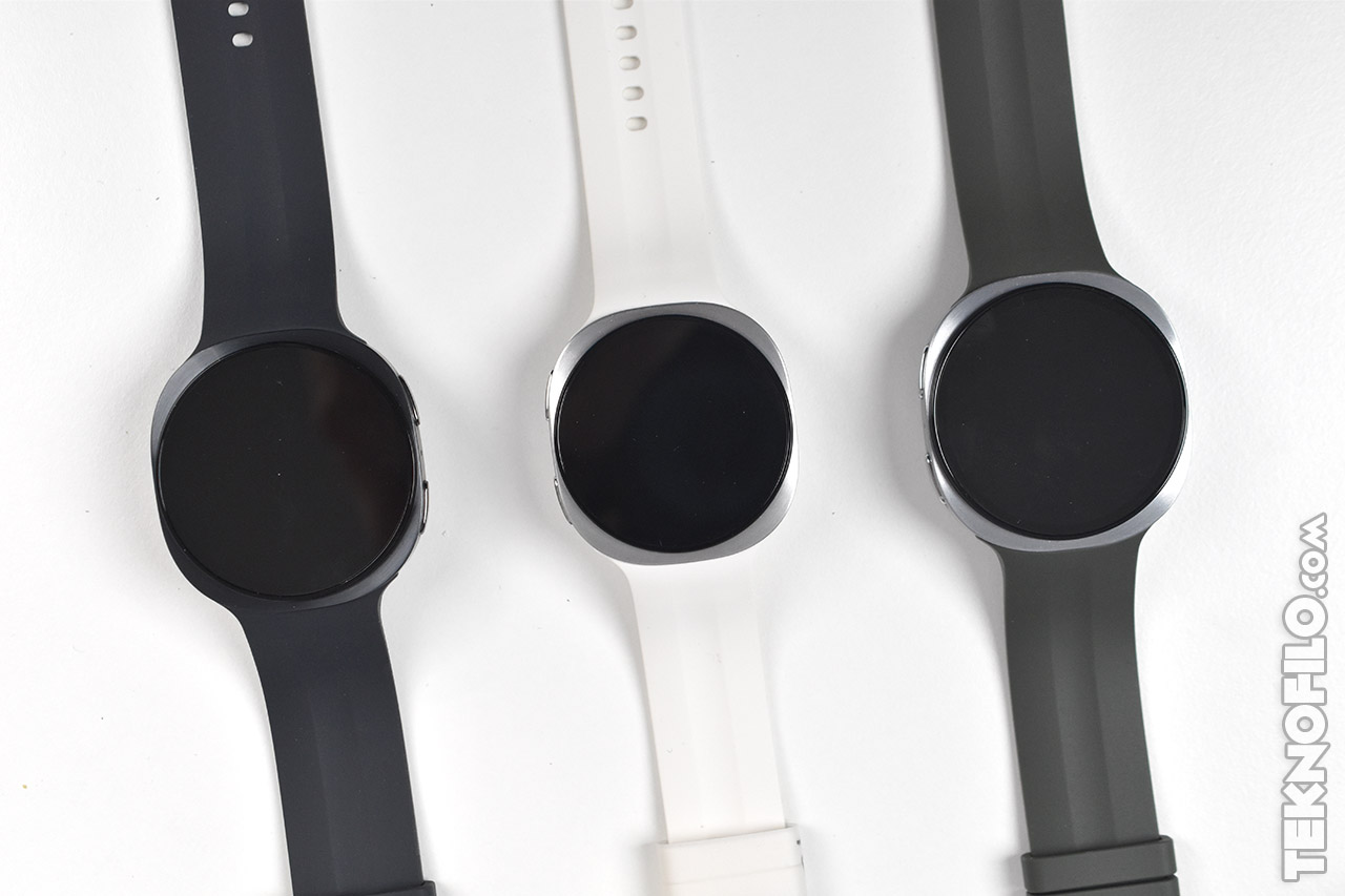 Tres relojes inteligentes con correas de silicona en negro, blanco y gris sobre fondo blanco.