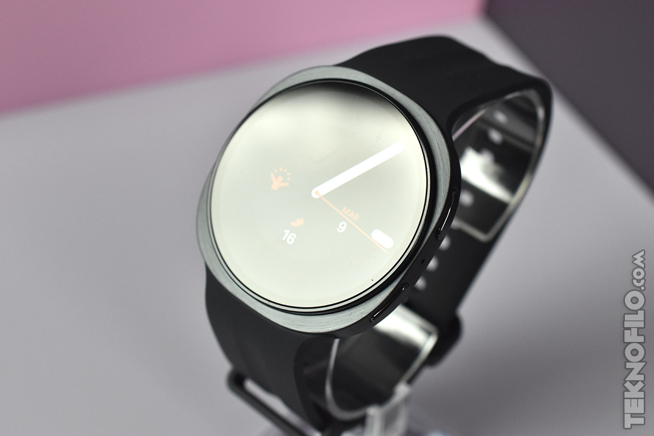 Reloj inteligente moderno con pantalla circular y correa negra sobre soporte, diseño minimalista elegante.