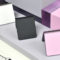 Tres smartphones plegables en colores blanco, negro y rosa sobre una mesa moderna.