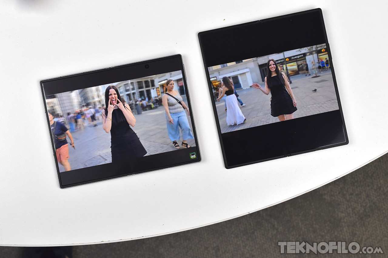 Dos pantallas mostrando fotos de personas en una plaza, sobre una mesa blanca.
