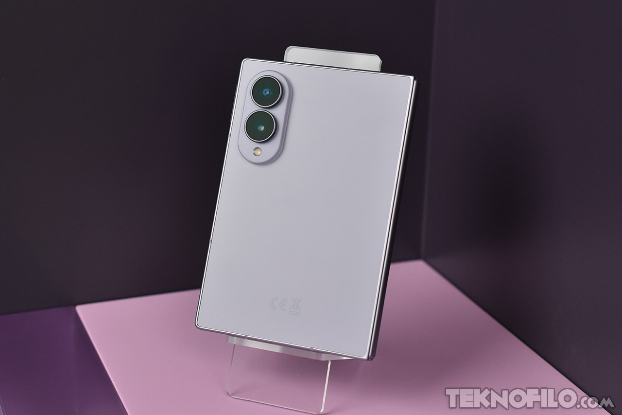 Teléfono plegable moderno sobre base, color violeta claro. Cámara dual y diseño elegante.
