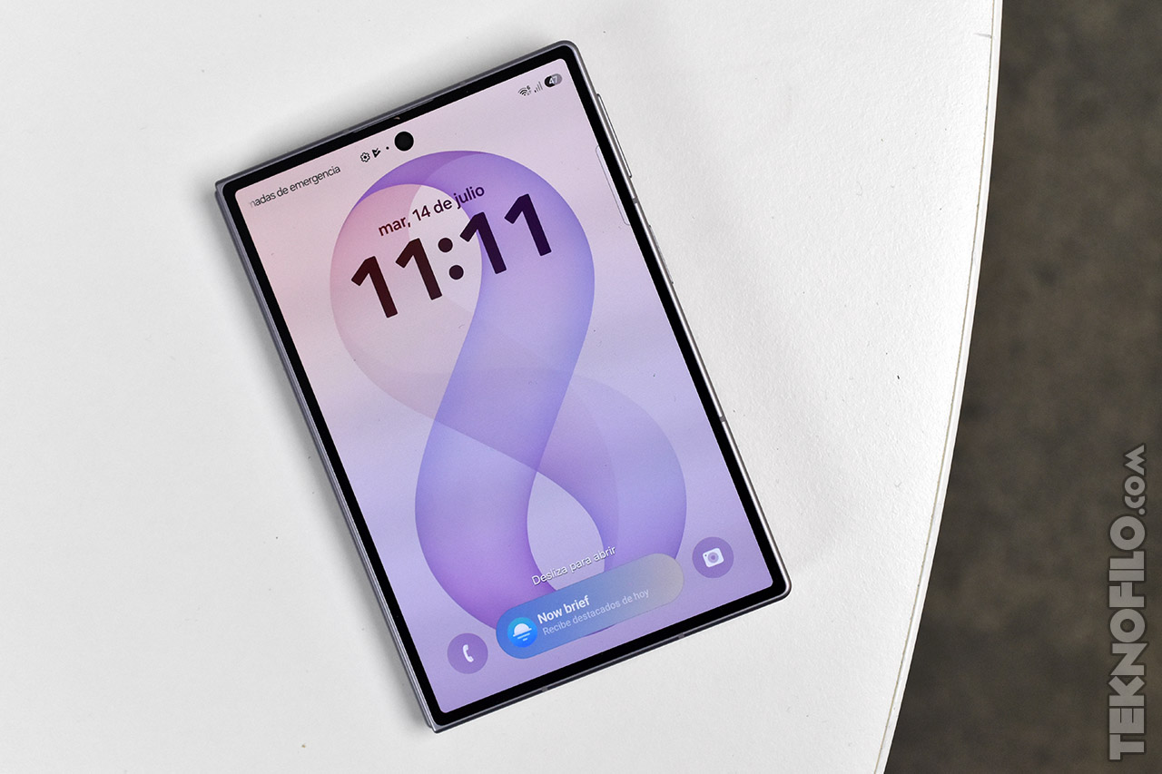 Pantalla de smartphone con fondo lila mostrando la hora 11:11 y fecha 14 de julio sobre mesa blanca.
