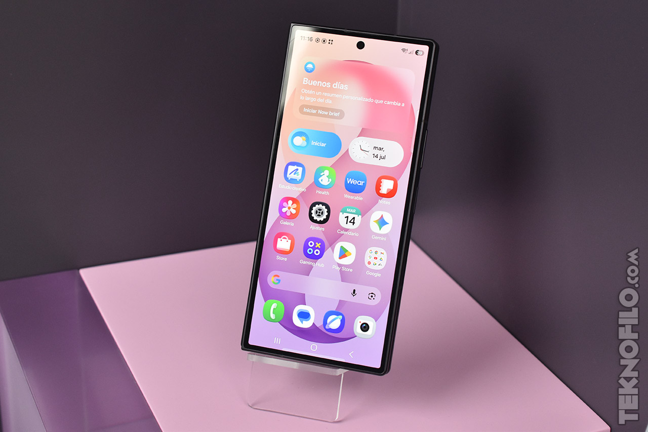 Smartphone moderno con pantalla encendida, mostrando diversas aplicaciones sobre fondo rosa y púrpura.