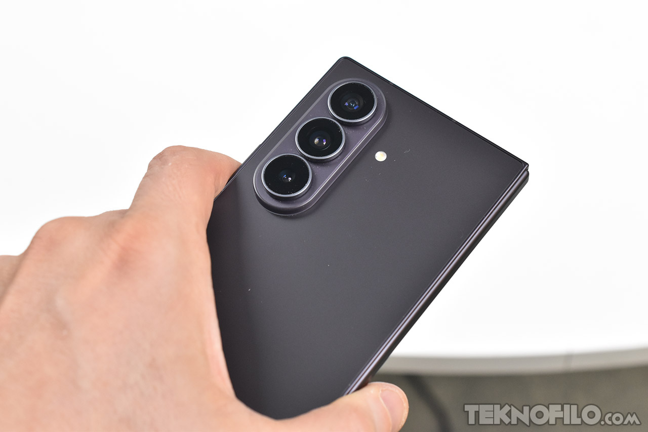 Teléfono plegable con triple cámara trasera en mano, diseño moderno y elegante.