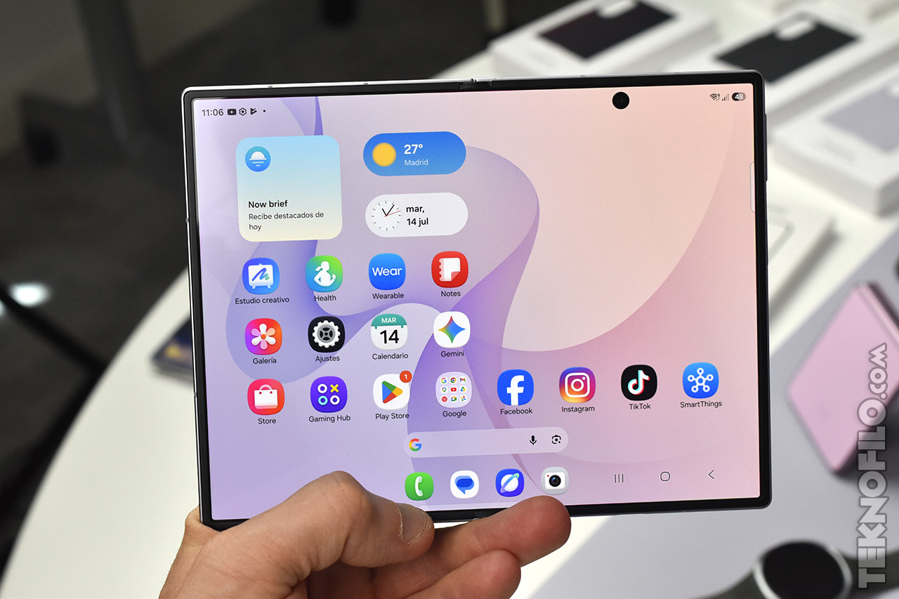 Pantalla plegable de smartphone mostrando varias aplicaciones y widgets en un fondo claro.