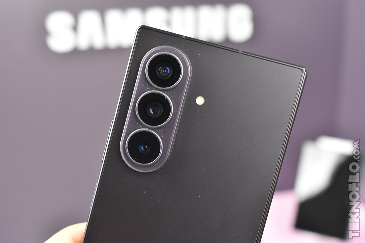 Smartphone Samsung con triple cámara trasera y flash, fondo desenfocado.