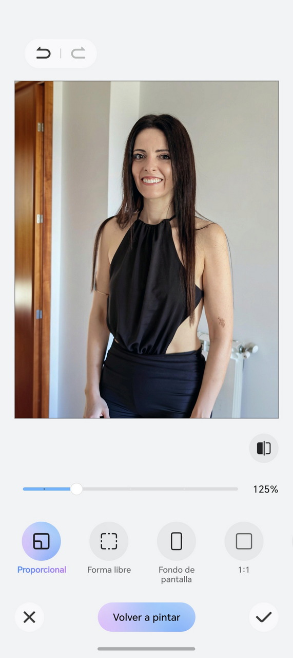 Mujer joven sonriendo, vestida de negro, de pie en una habitación luminosa.