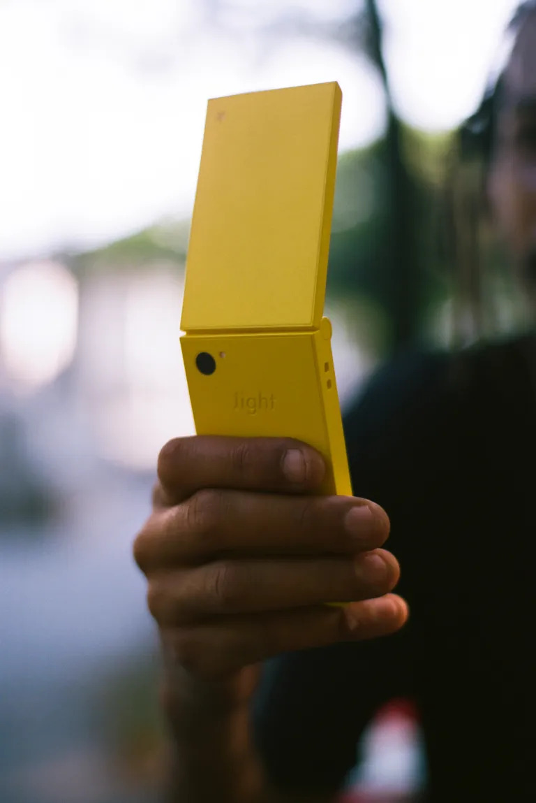 Teléfono plegable amarillo en mano, enfoque en el diseño minimalista.