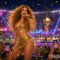 Shakira arrasa en Apple Music y Shazam tras actuar en la final del Mundial Cantante actuando en concierto, con vestuario dorado y multitud celebrando en un estadio iluminado.