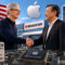 Apple y Broadcom sellan un acuerdo histórico para producir 15.000 millones de chips en EE. UU. Ejecutivos estrechando manos por inversión de Apple y Broadcom en chips fabricados en EE.UU., con bandera de fondo.